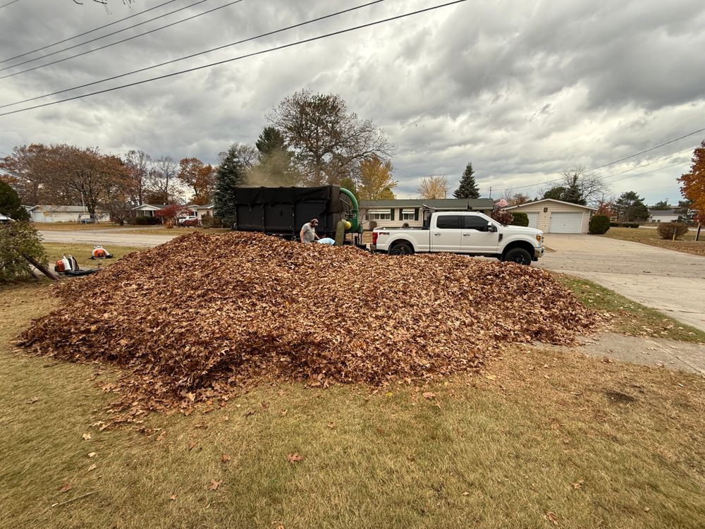 A white truck is parked in front of a pile of leaves.