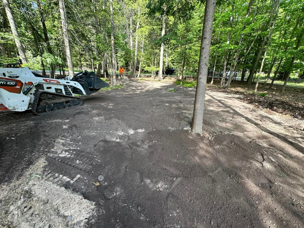 A bulldozer is sitting in the middle of a dirt road in the woods.