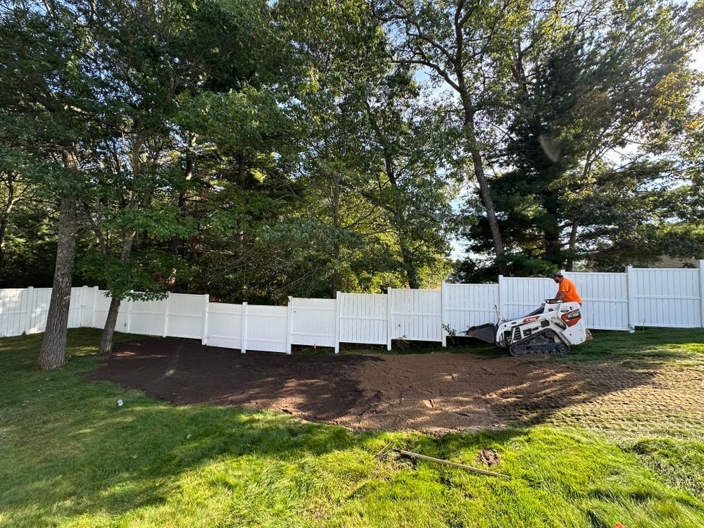 A man is using a machine to remove a tree stump in a backyard.