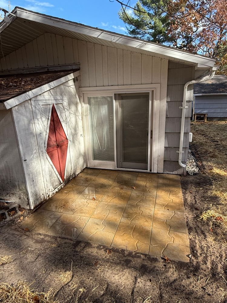 A white house with a sliding glass door and a patio in front of it.