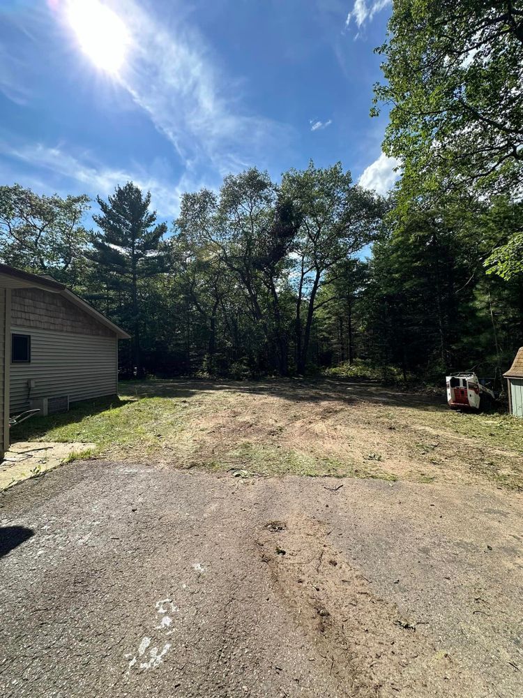 A dirt road leading to a house with trees in the background.