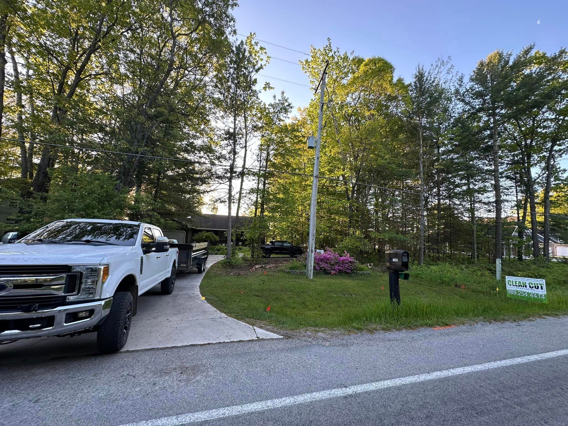 A white truck is parked on the side of the road in front of a house.