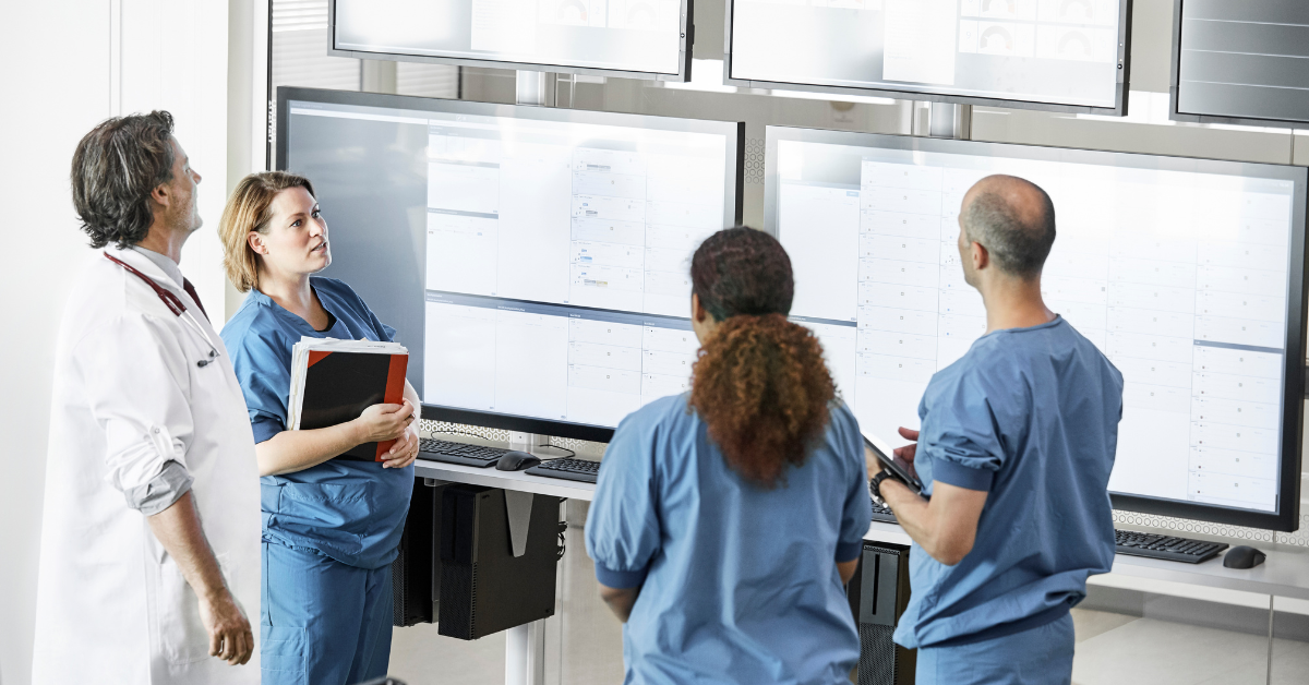 Medical team looking at data on multiple computer screens.