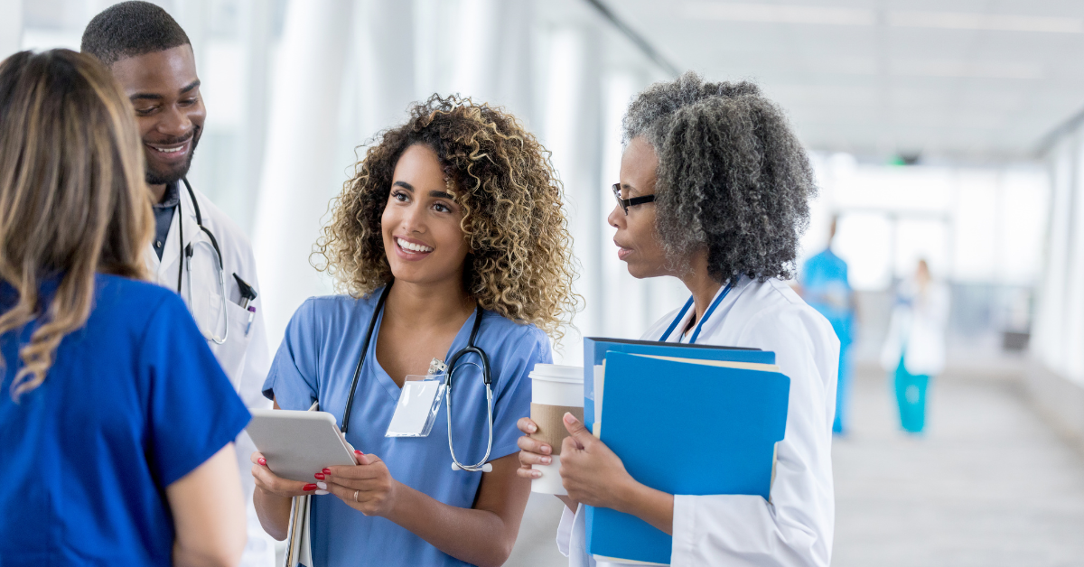Medical professionals in a brightly lit hallway discussing patient information.