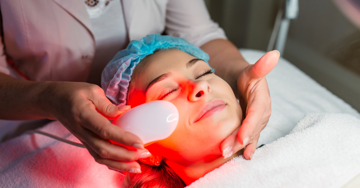 Woman receiving red light therapy treatment on face at a spa.