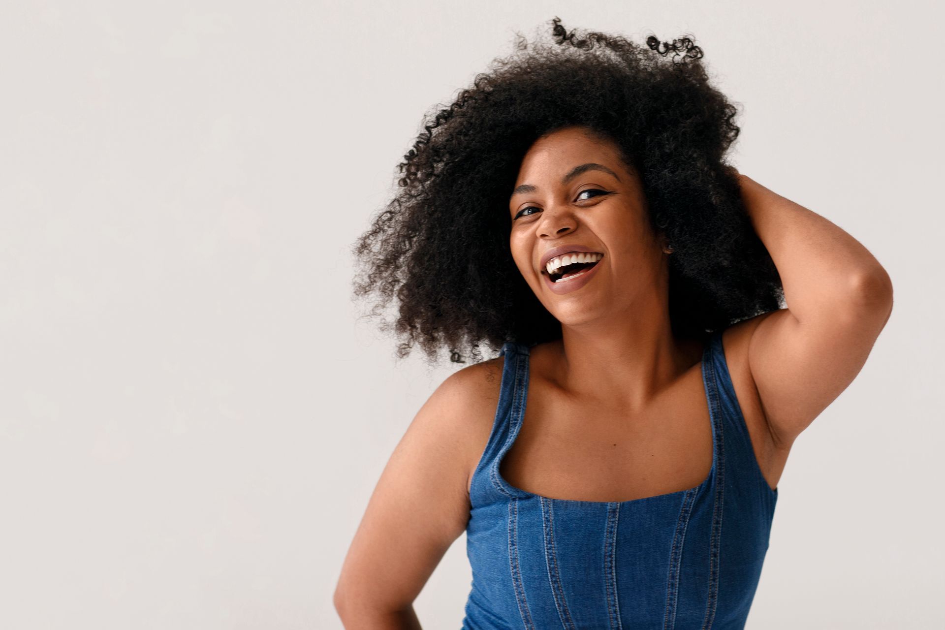 Woman with dark curly hair smiles widely