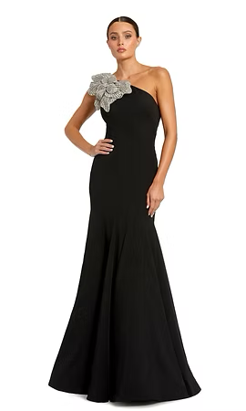 Woman in black one-shoulder gown with floral embellishment, posing.