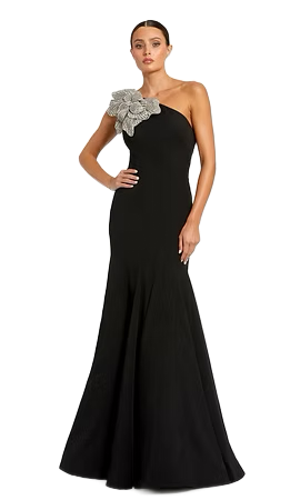 Woman in black one-shoulder gown with floral embellishment, posing.