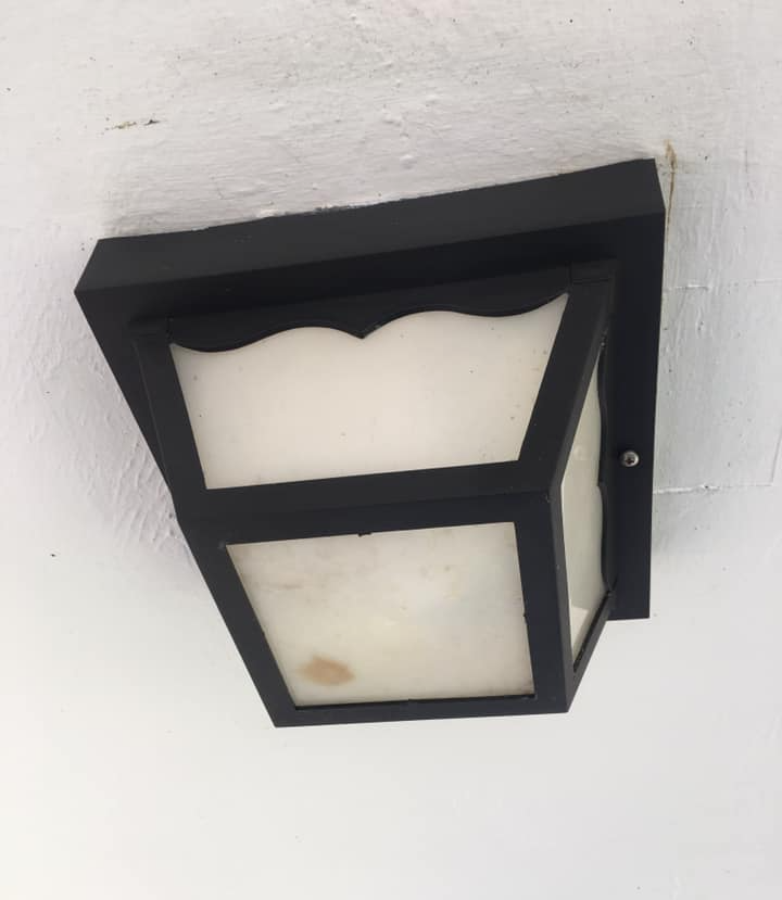 A black wall light with a white glass shade
