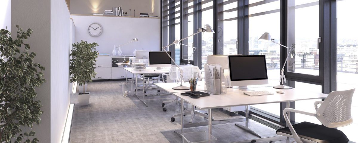 An office with a lot of windows and tables with computers on them.