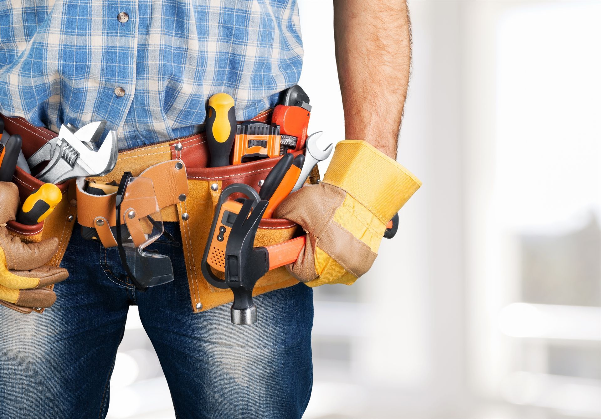 A man is wearing a tool belt and holding a tool in his hand.