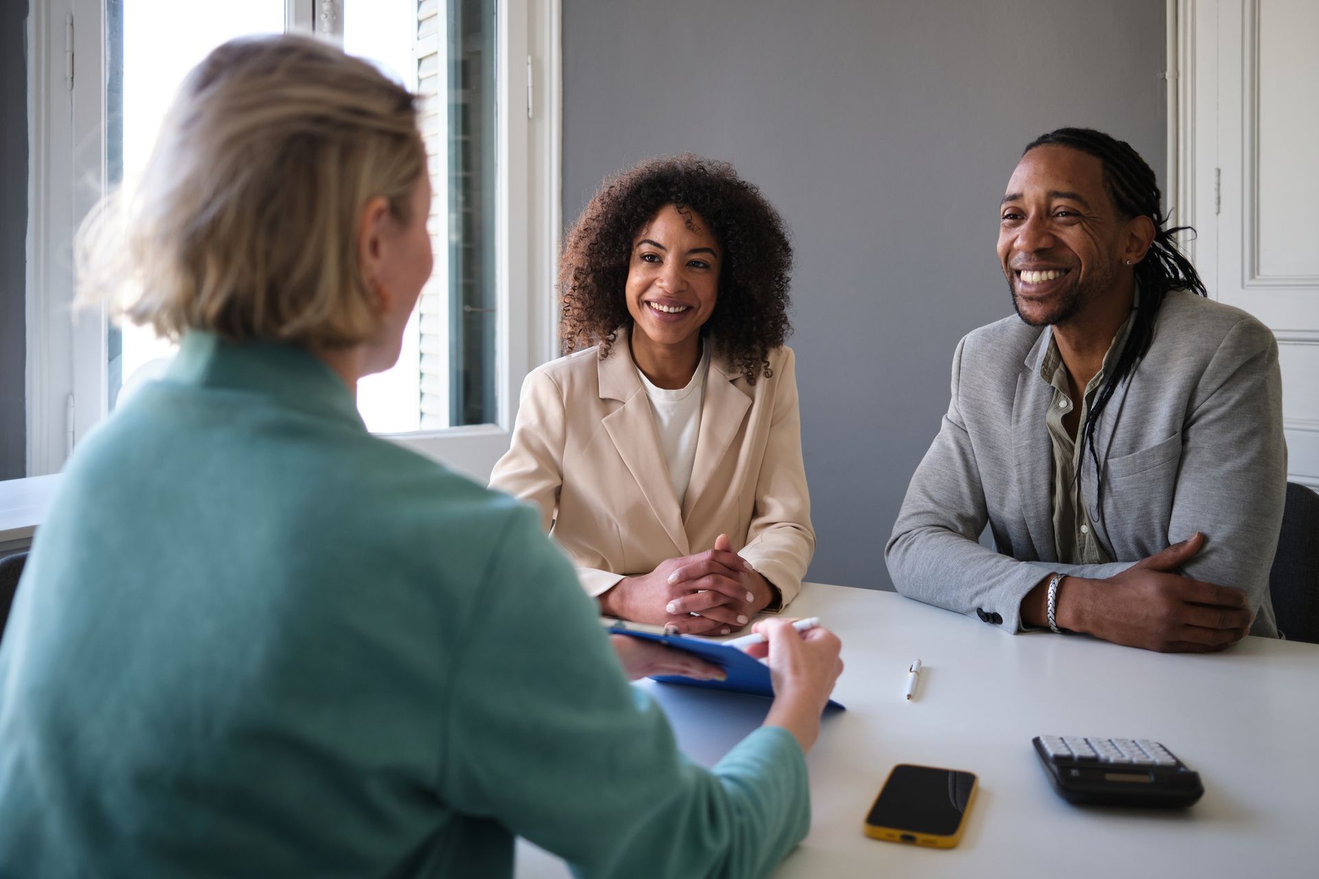 Businesswoman signing a contract with couple at a business insurance agency.
