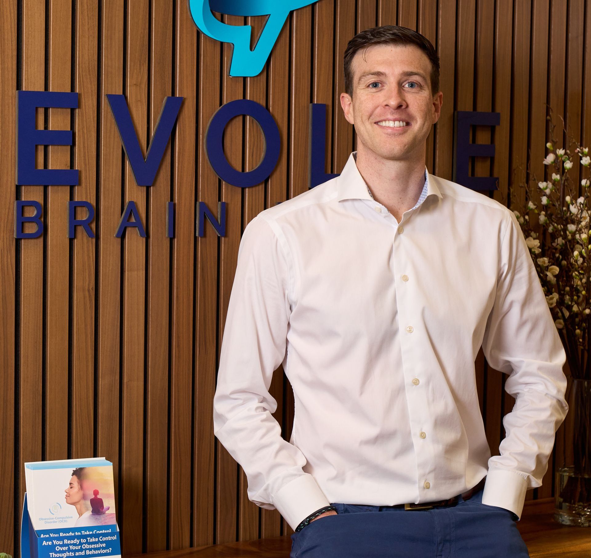 A man stands in front of a sign that says evolve brain