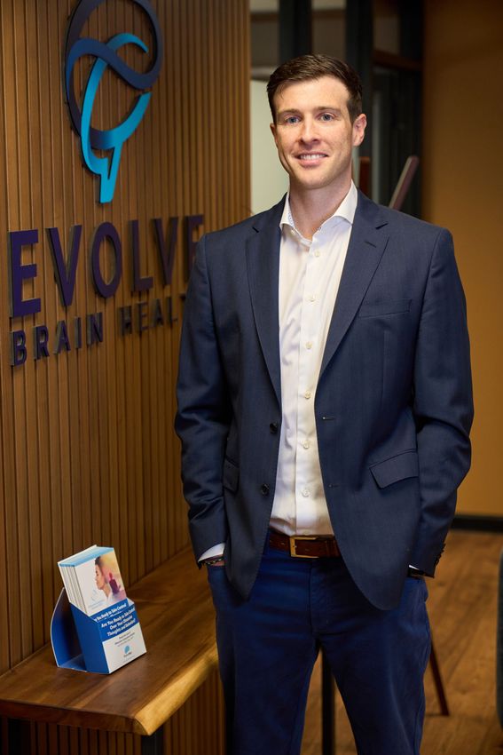 A man in a suit is standing in front of a sign that says evolve brain health.