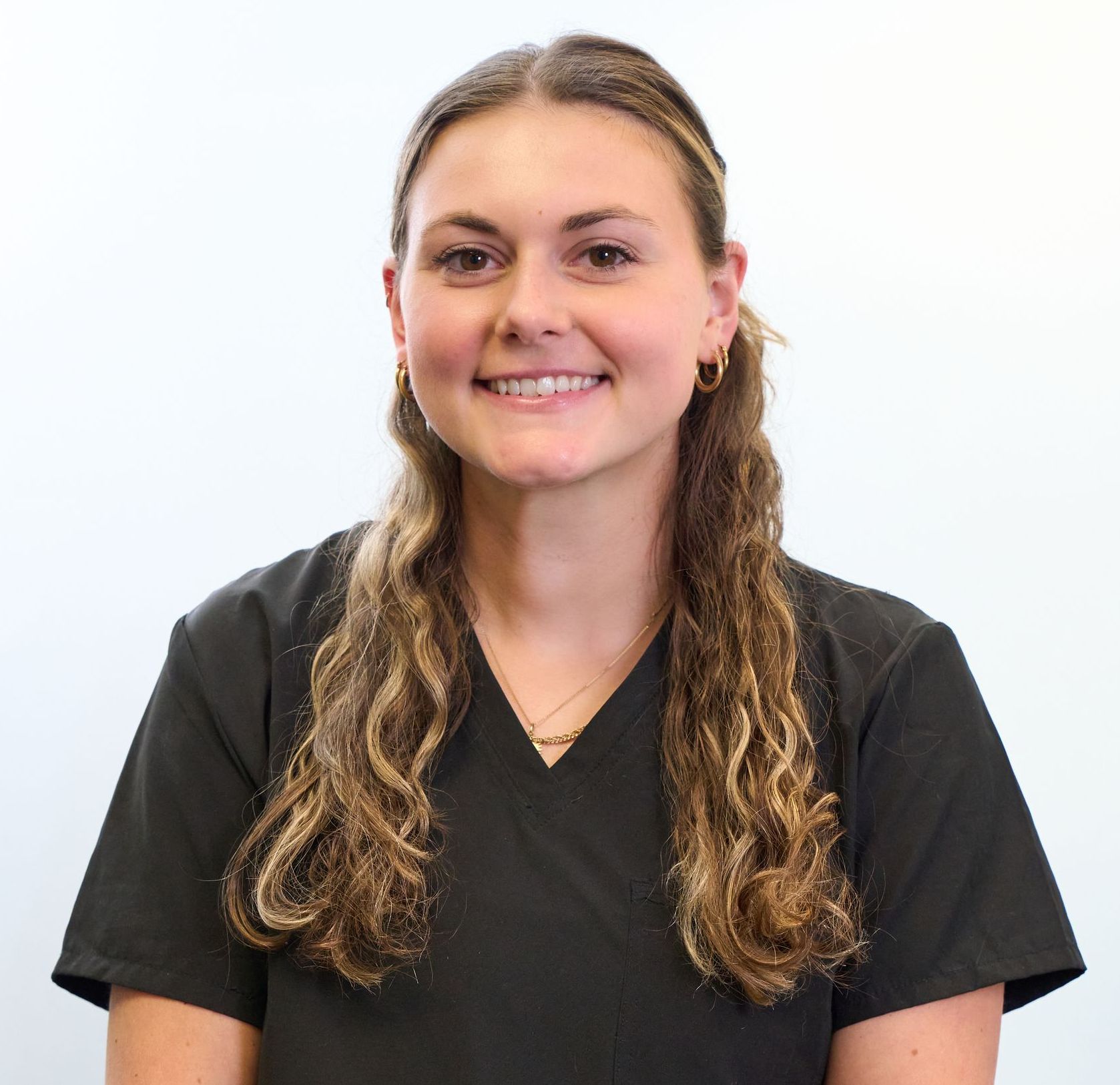 A woman in a black scrub top is smiling for the camera.