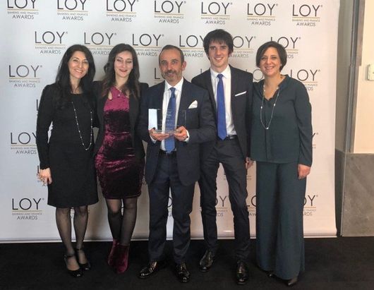 Un gruppo di persone in piedi davanti a un muro su cui è scritto loy