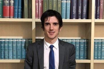 Un uomo in giacca e cravatta è in piedi davanti a una libreria.