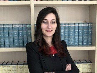 Una donna è in piedi davanti a una libreria con le braccia incrociate.