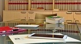 Un tavolo di vetro con un tablet e dei documenti sopra.