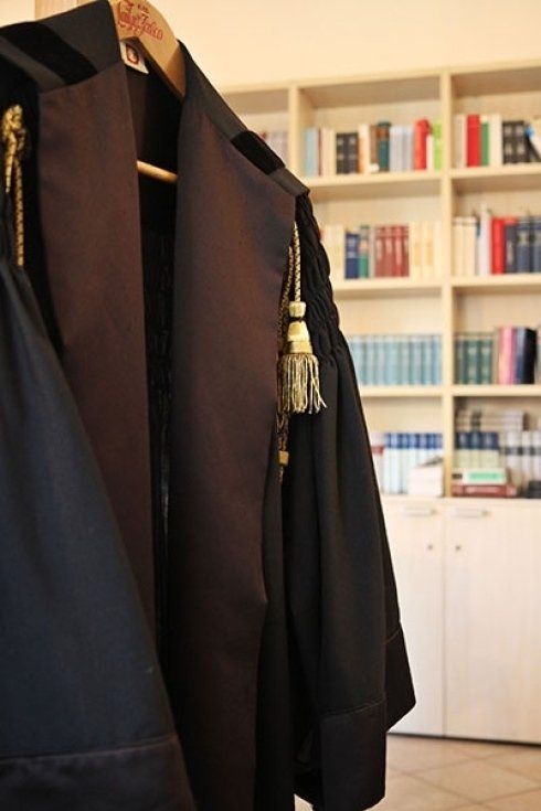 La toga di un giudice è appesa a una gruccia davanti a una libreria.