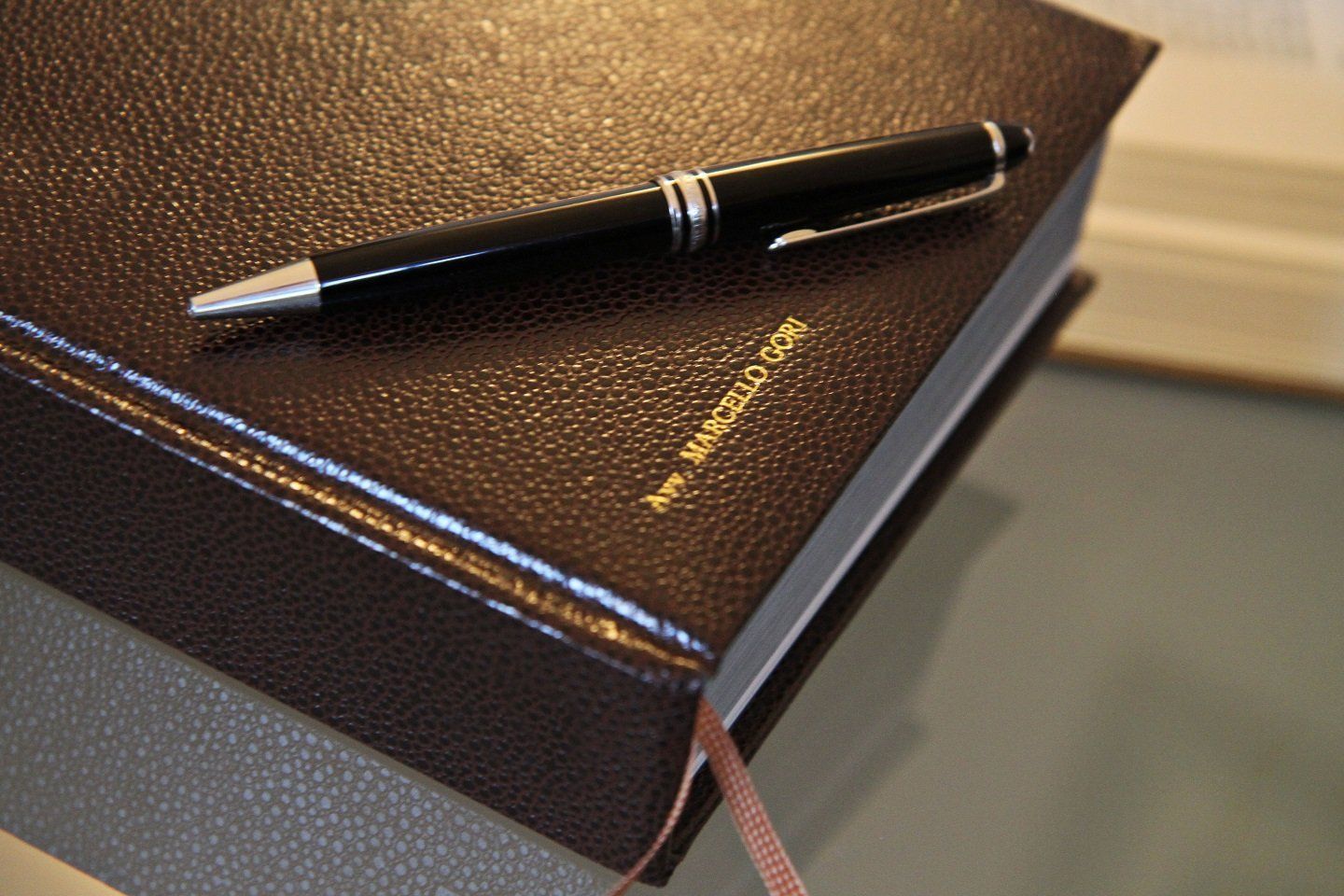 Una penna poggia sulla parte superiore di un libro rilegato in pelle marrone
