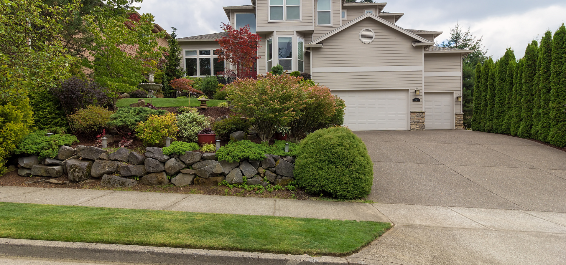 A house with a nice driveway and beautiful landscaped garden next to it