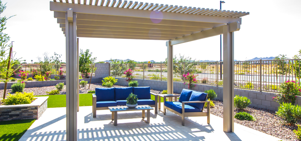 A white pergola on a patio, with a blue sofa in it