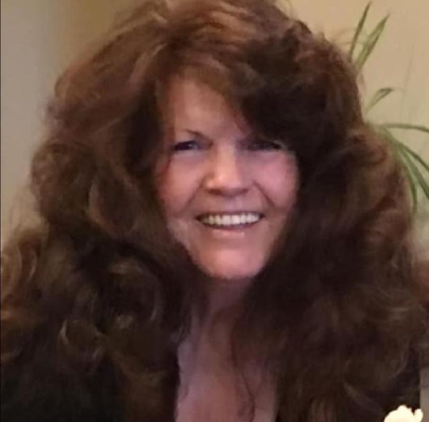 A woman with long brown hair is smiling for the camera.