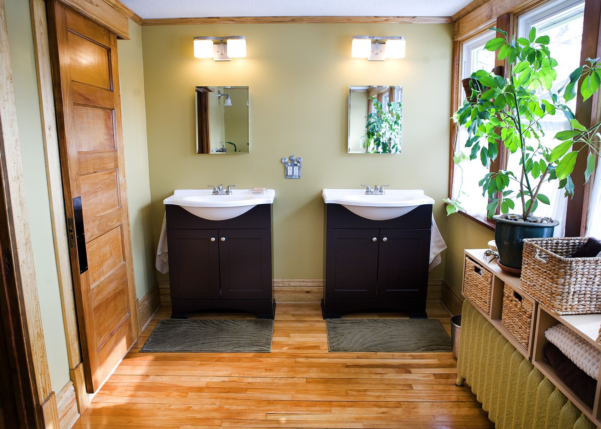 A bathroom with two sinks and a plant in the window.