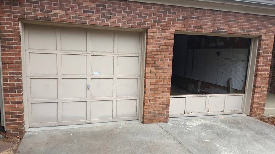 A tan garage door with one side fully raised and the other side closed, set into a brick exterior wall.