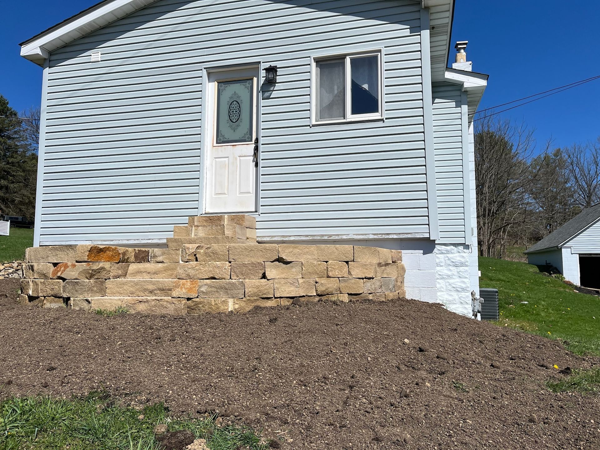 A small white house with stairs leading up to the front door.