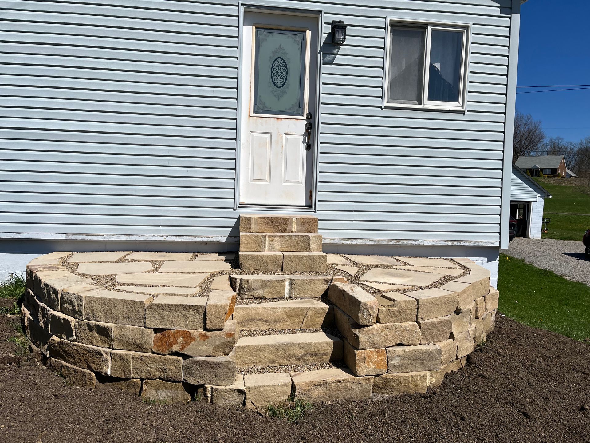 A house with a stone porch and stairs leading to the front door.