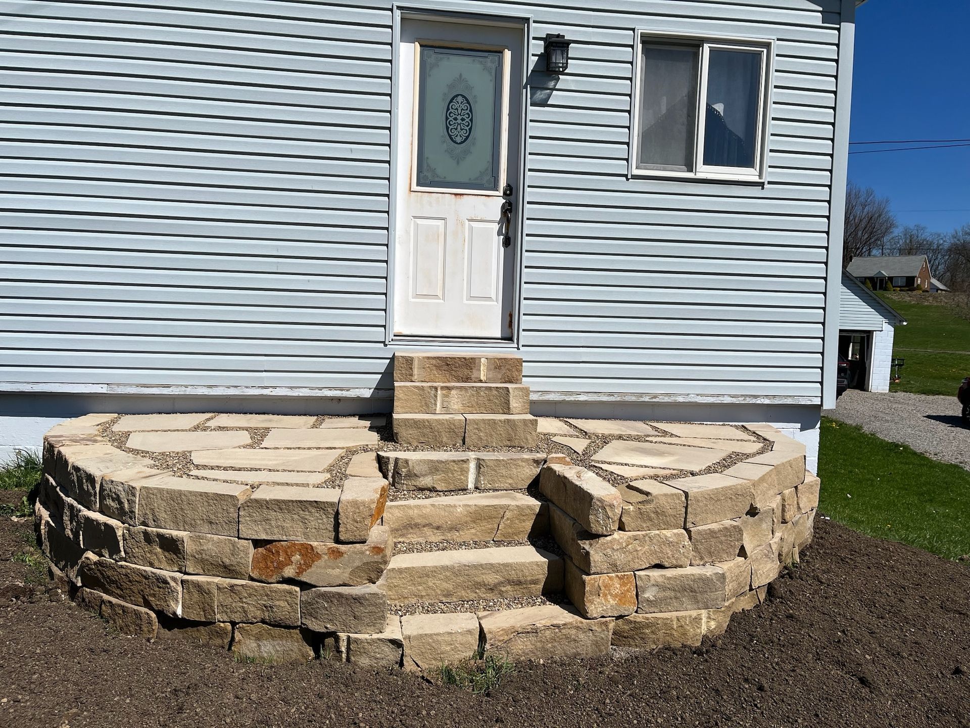 A house with a stone porch and stairs leading to the front door.