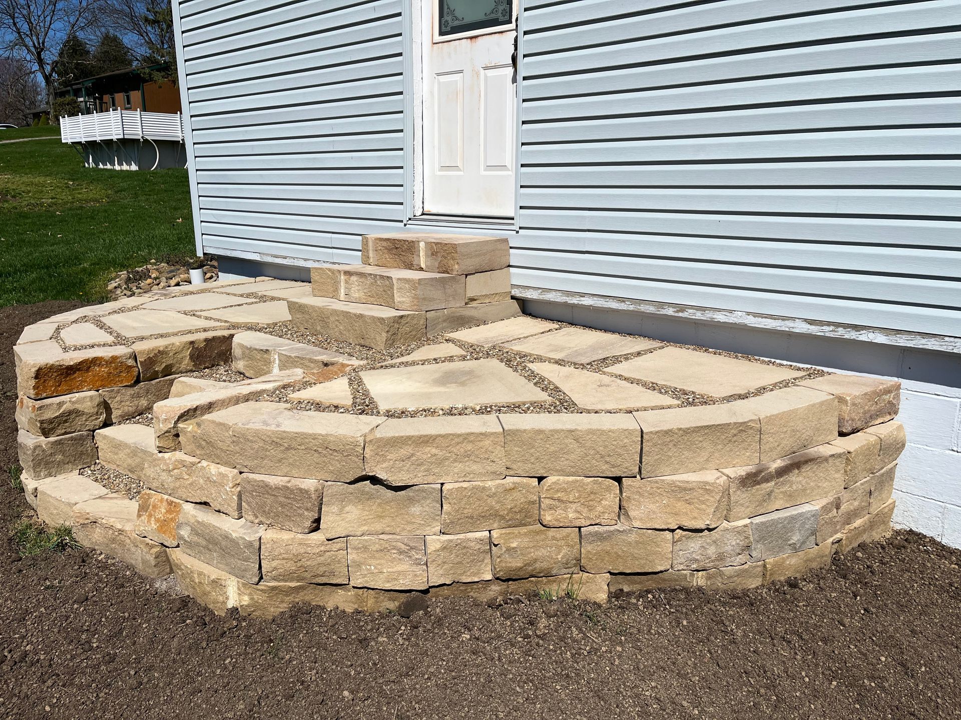 A stone walkway is being built in front of a house.
