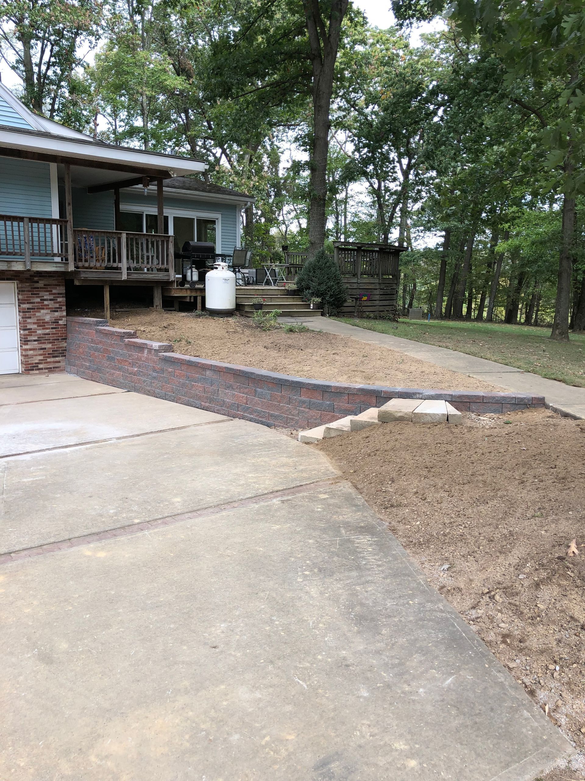 A house with a brick wall and a propane tank in front of it