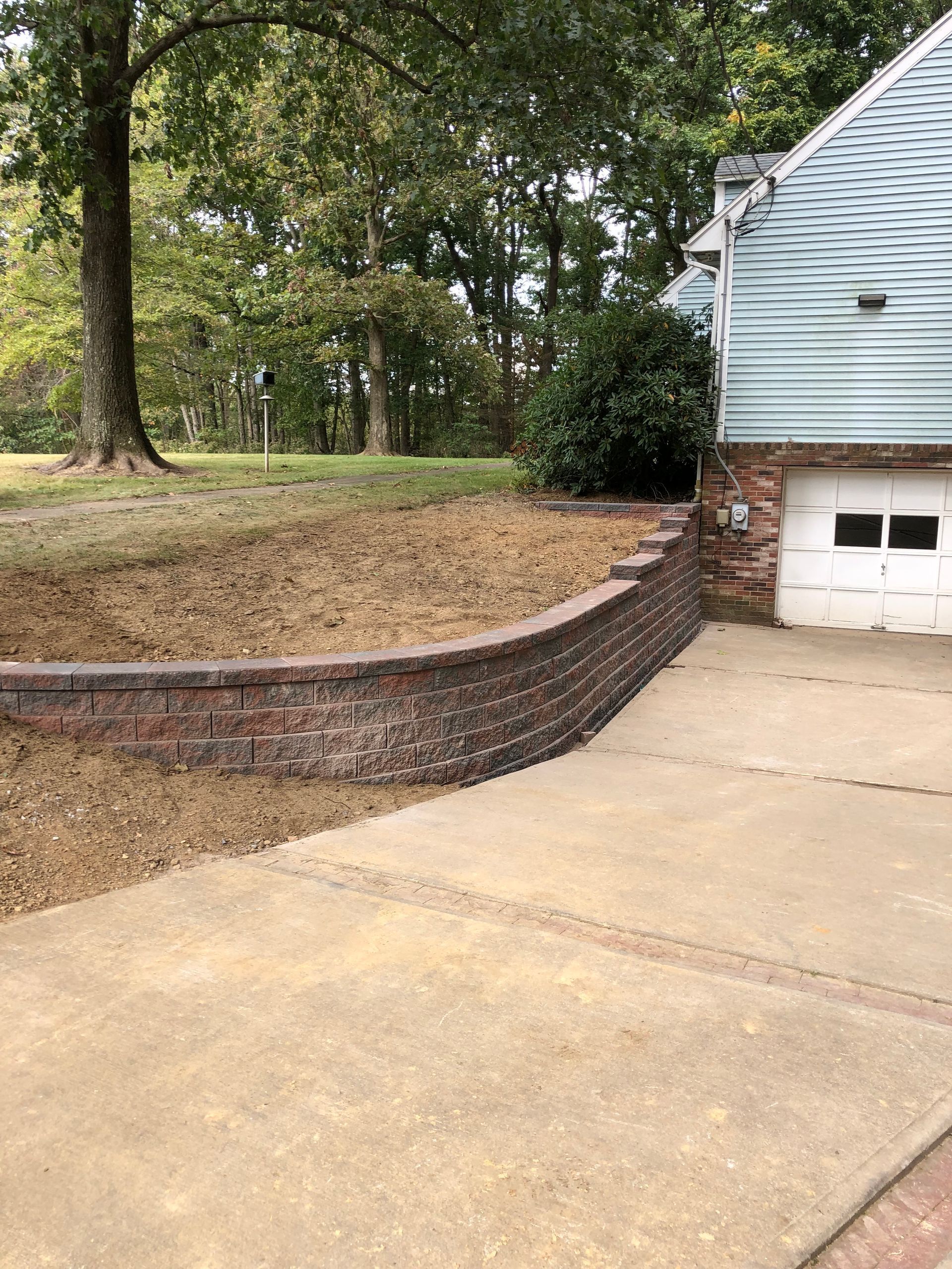 A driveway with a brick wall and a garage next to a house.