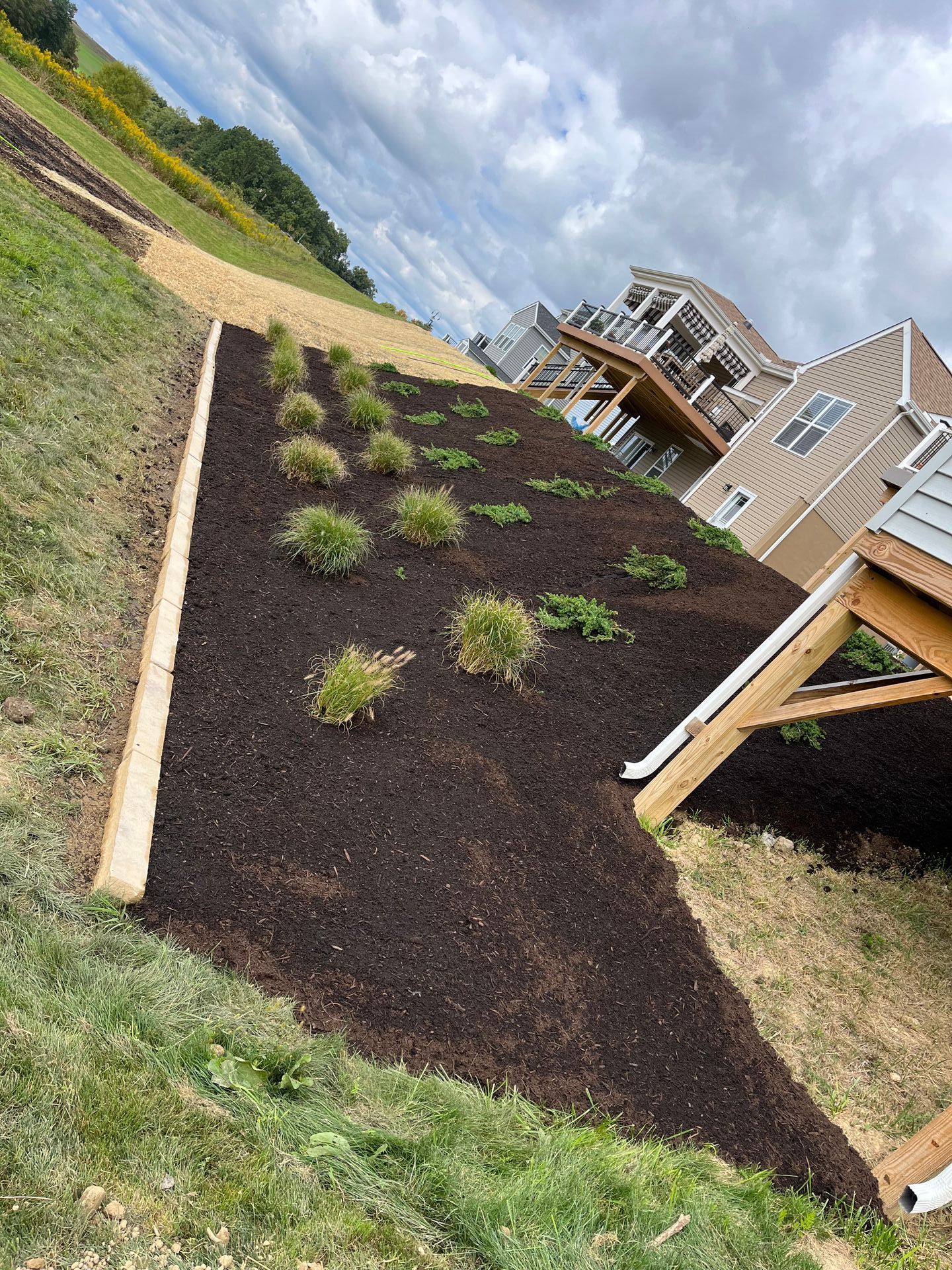A house is sitting on top of a hill next to a lush green field.
