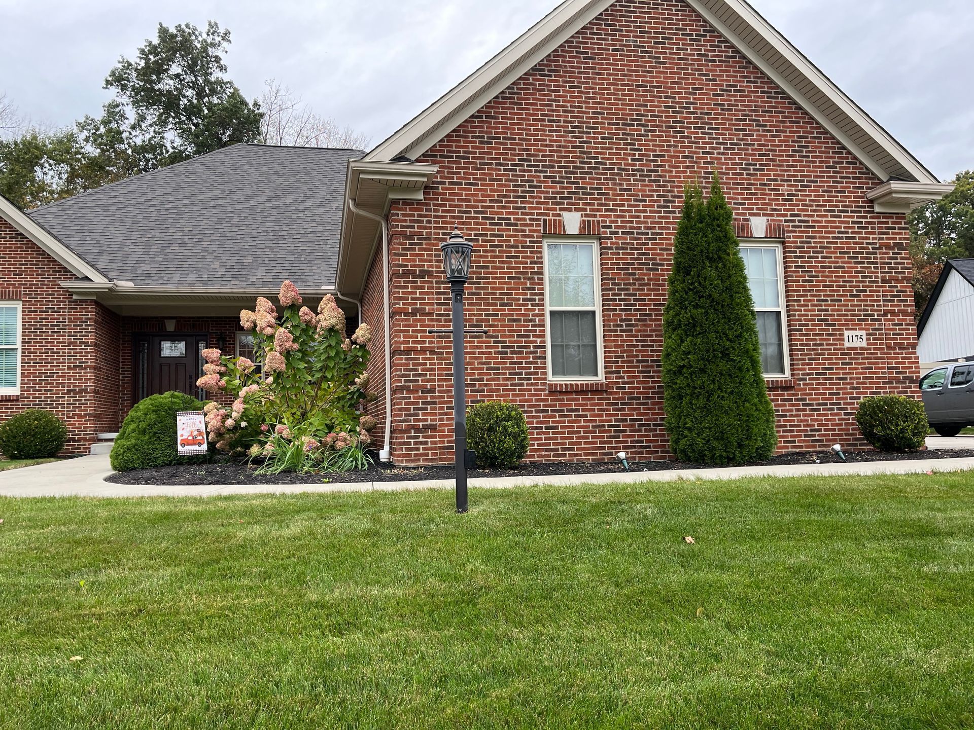 A brick house with a lush green lawn in front of it.
