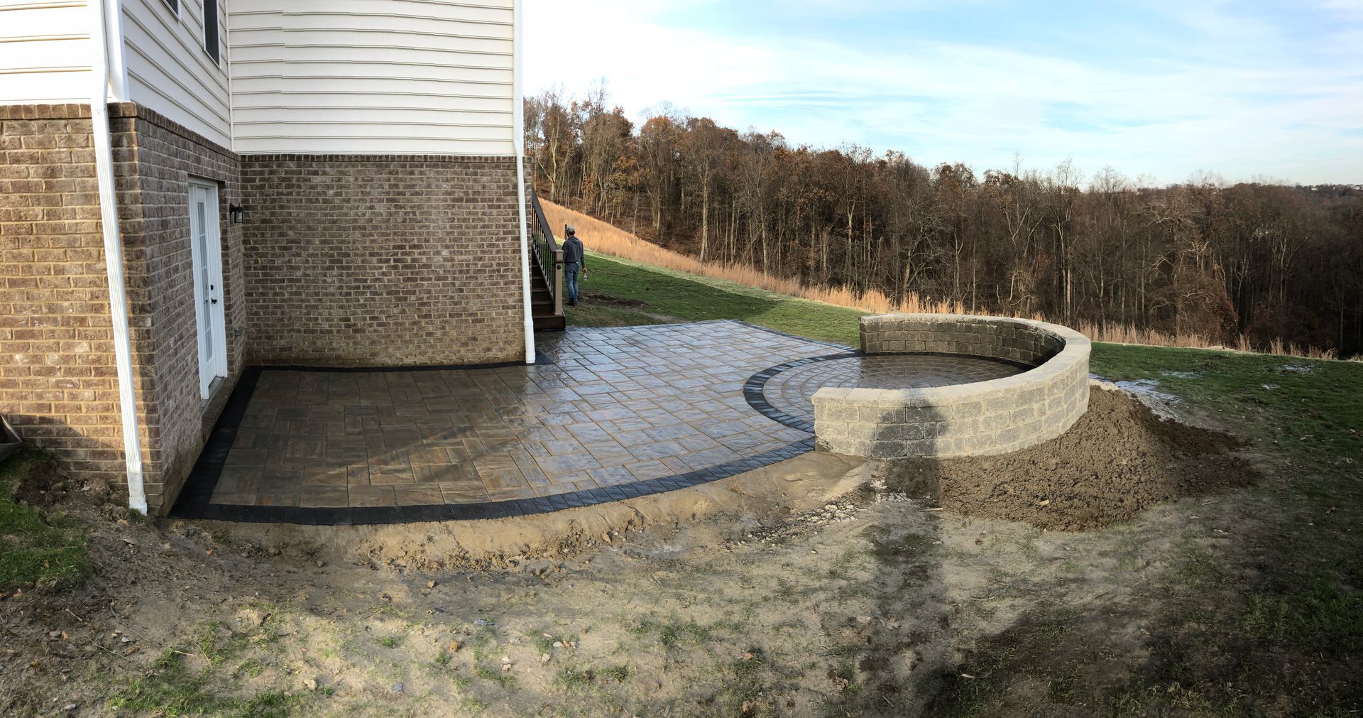 A patio is being built in front of a brick house.