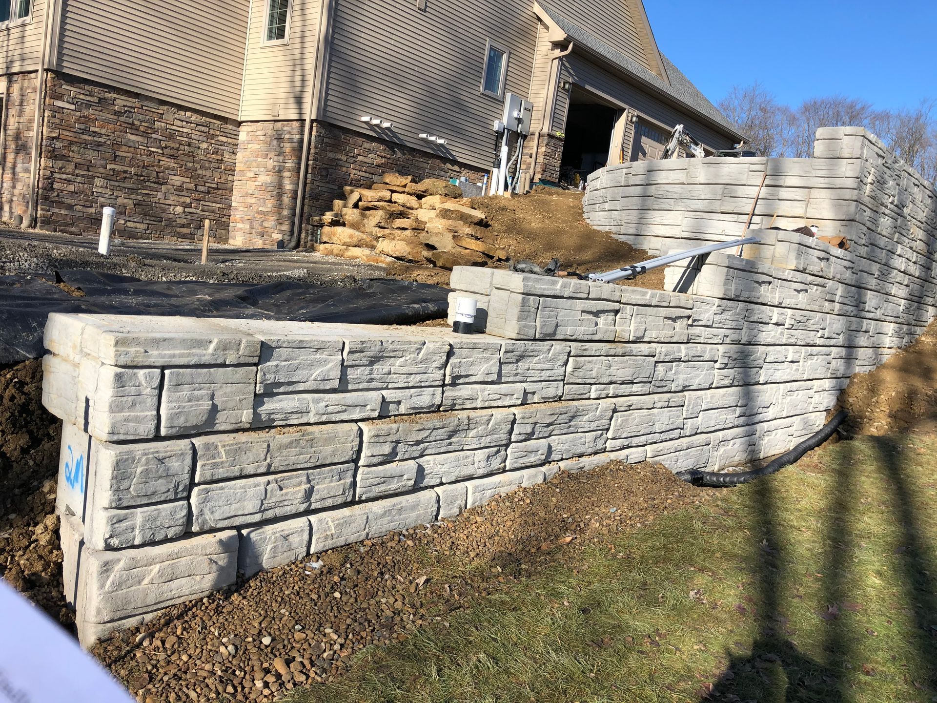 A large stone wall is being built in front of a house.