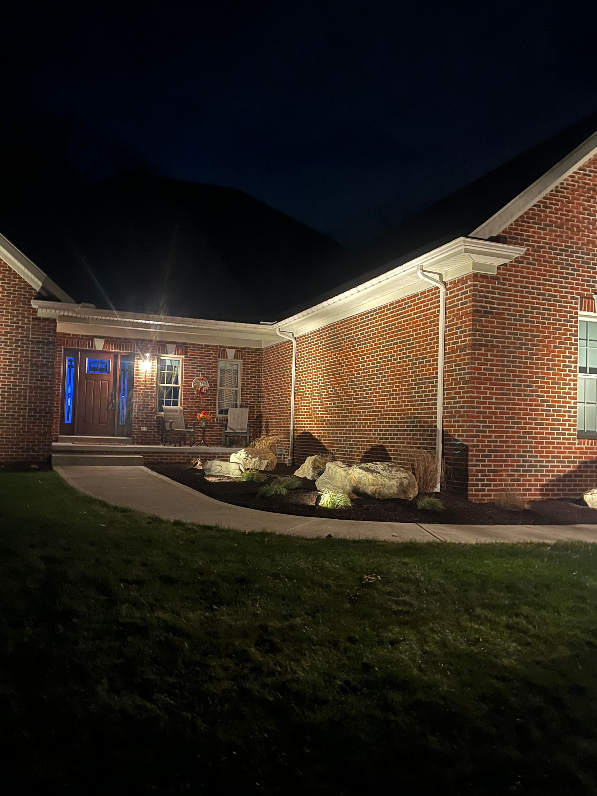 The front of a brick house is lit up at night.