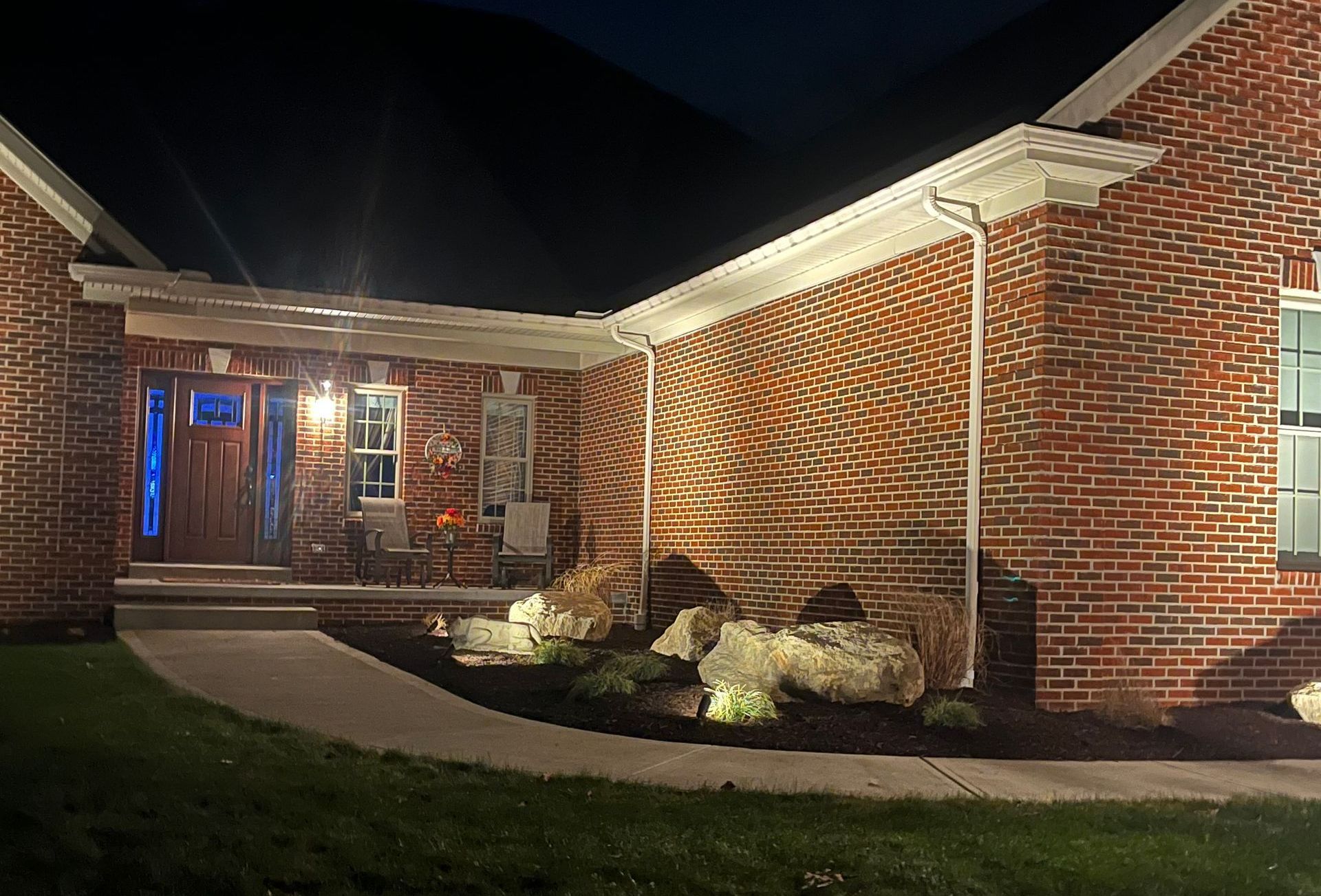 The front of a brick house is lit up at night.