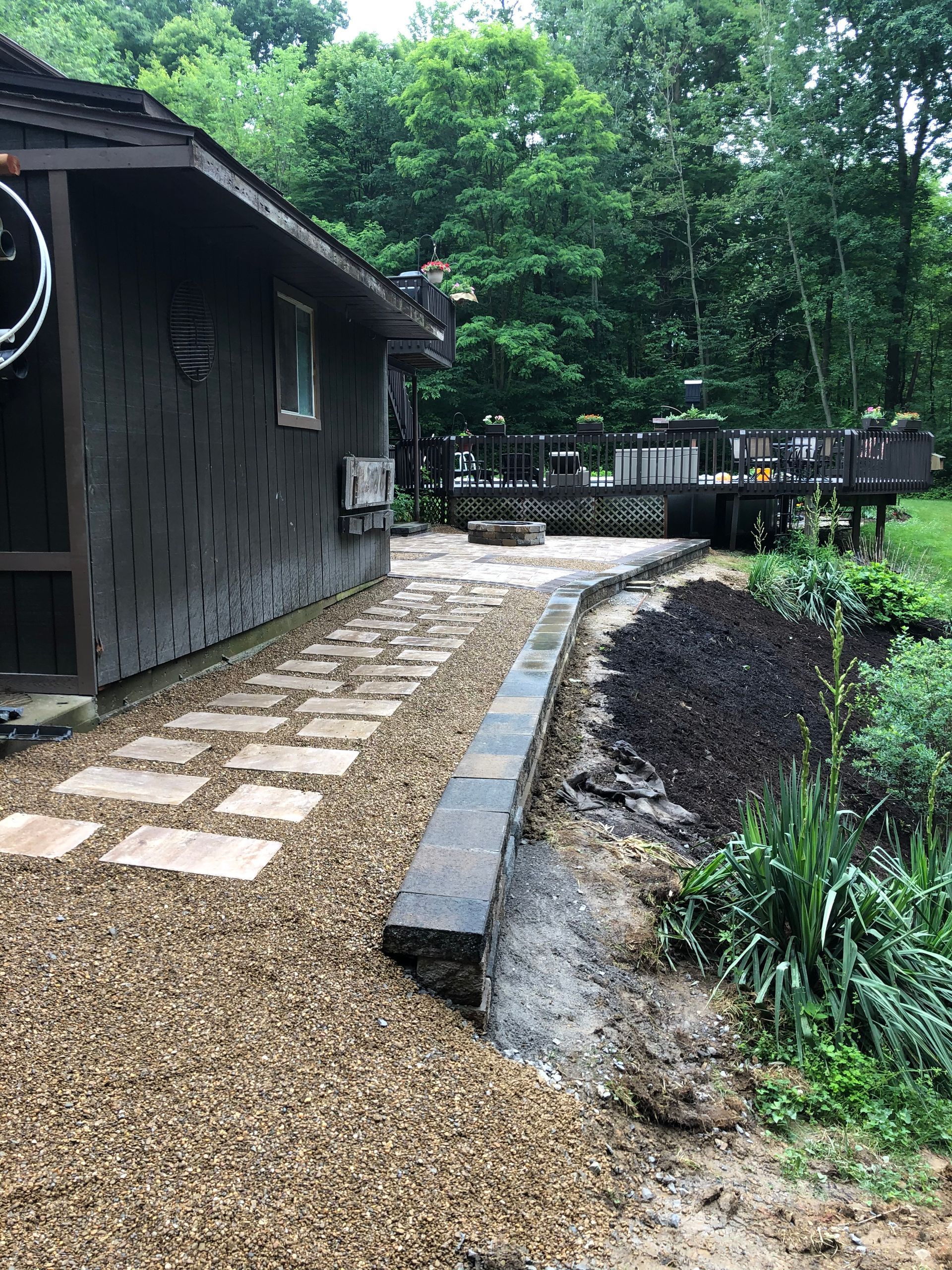 A stone walkway leading to a house in the woods.