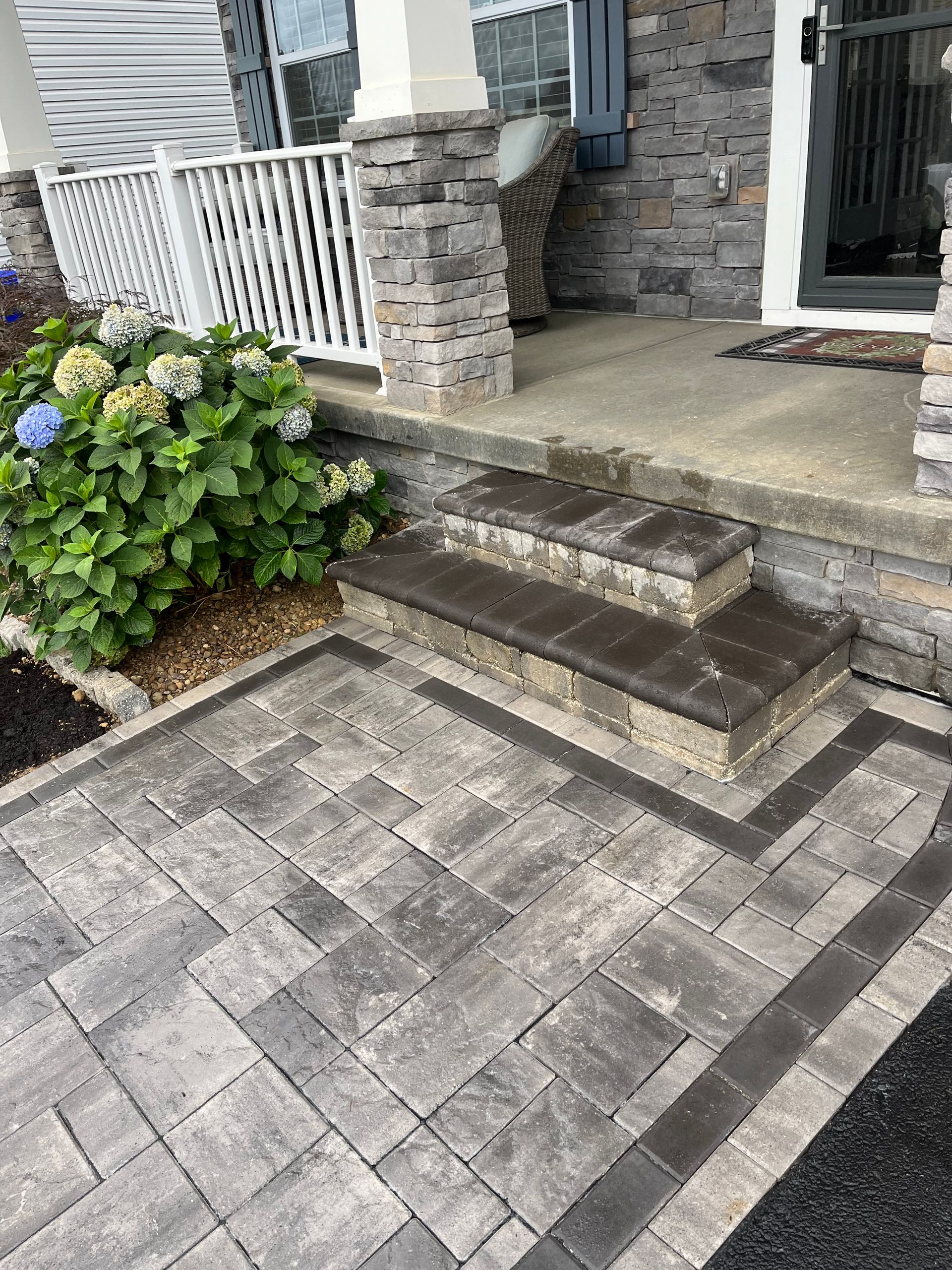 A brick walkway with steps leading up to a porch of a house.