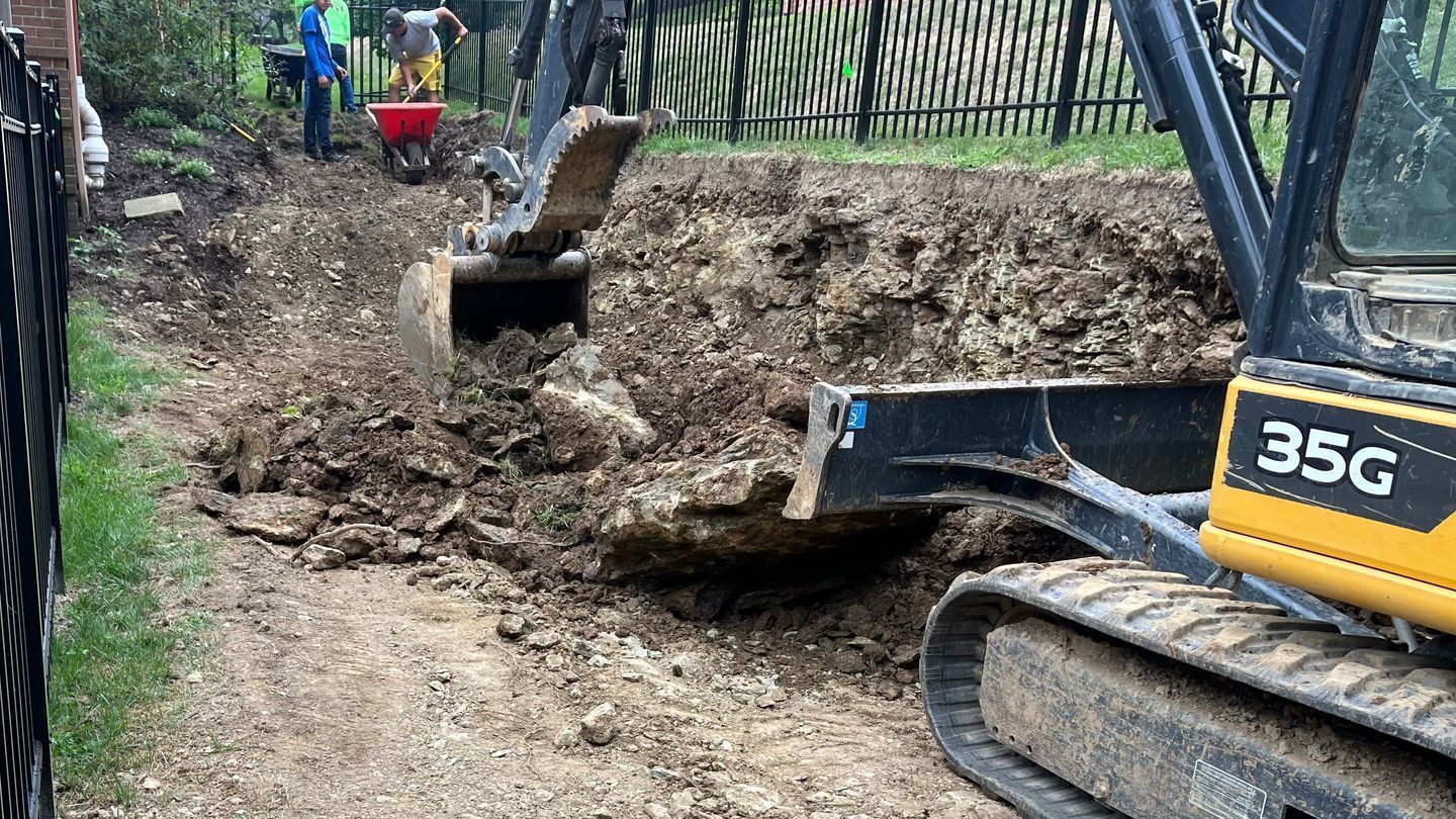 A yellow and black excavator is digging a hole in the dirt.