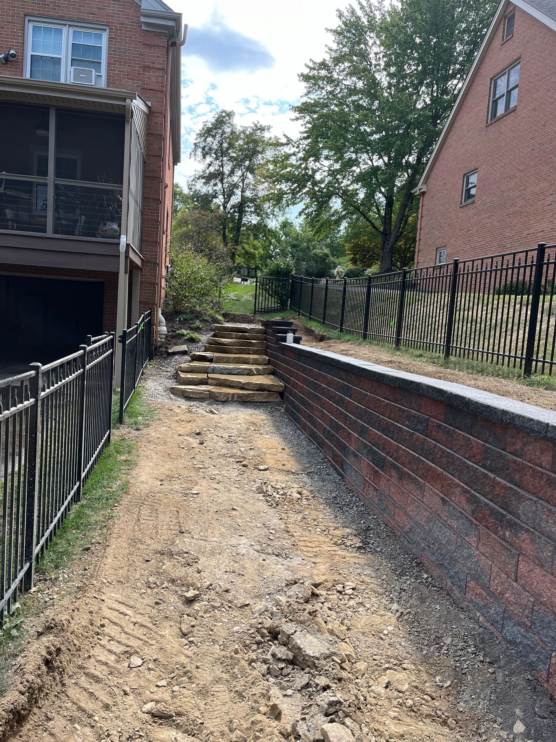 A brick wall is being built in front of a brick house.