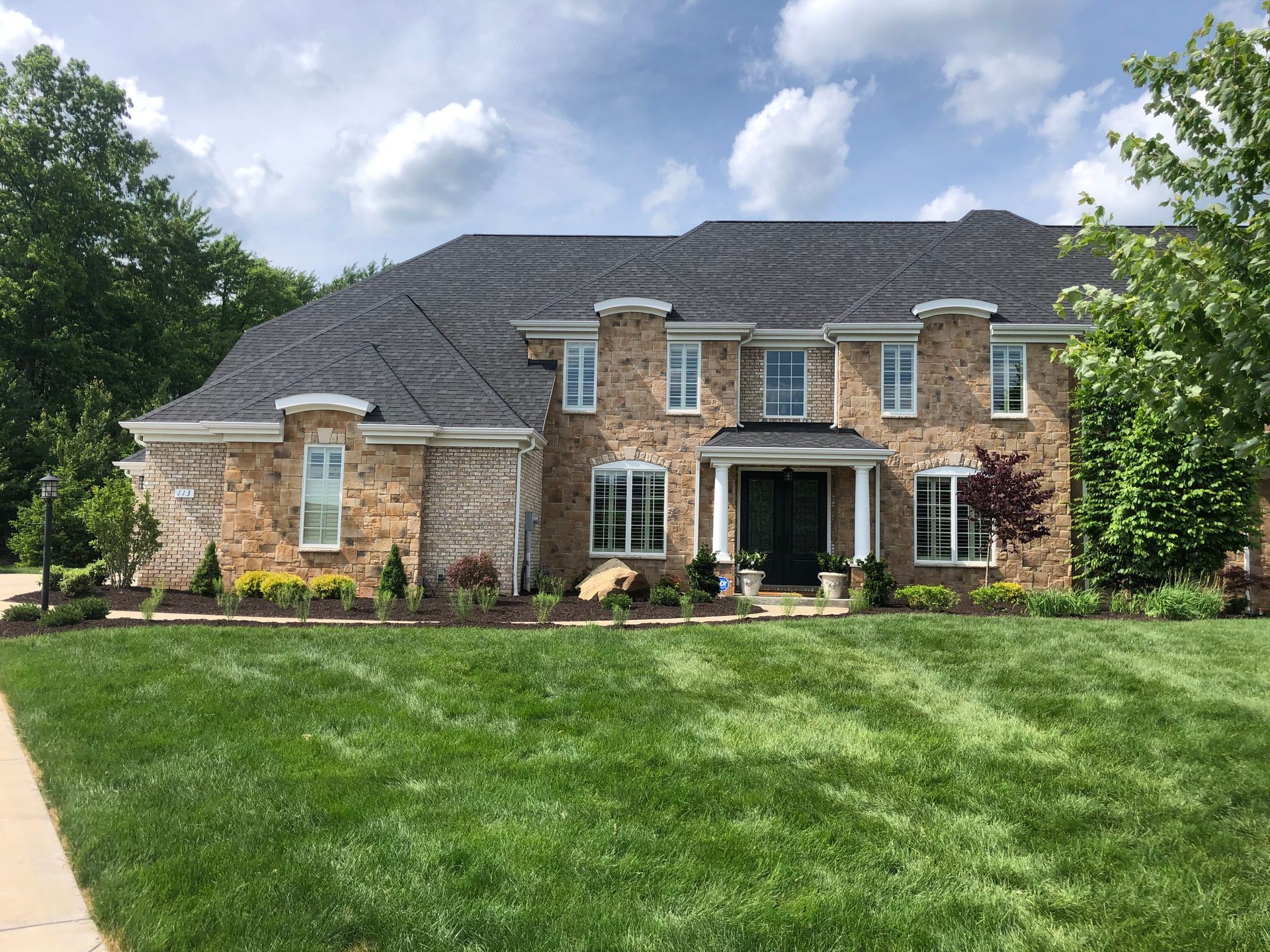 A large brick house with a lush green lawn in front of it.
