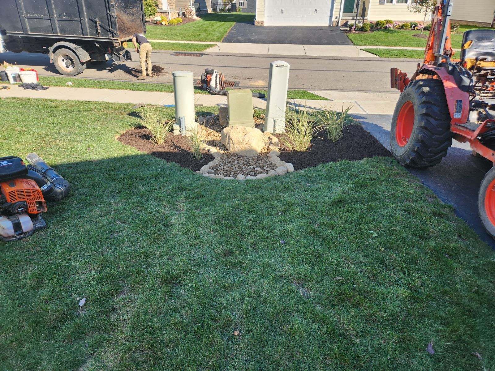 A lawn mower is sitting in the grass next to a tractor.