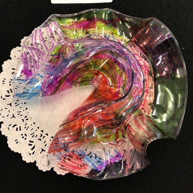 A colorful plastic container is sitting on a white lace napkin