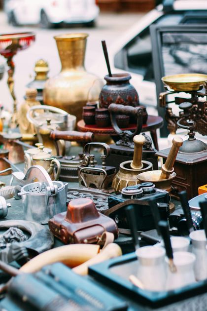 Assorted vintage metal teapots and kettles displayed at an outdoor market stall